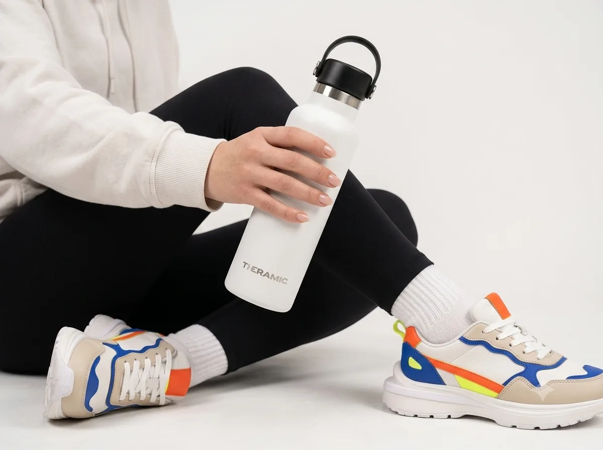 Persona sentada en el suelo con ropa deportiva sosteniendo una botella Theramic blanca